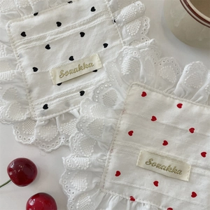 Detail of square lace coasters with heart patterns on a white table setting