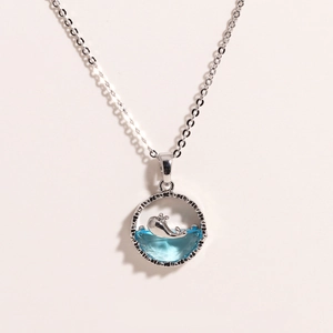 Close-up of whale pendant necklace featuring blue crystal and polished silver finish