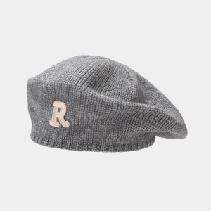 Detail of grey knitted beret featuring plush R letter patch and ribbed wool texture