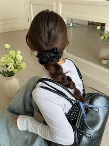 Détail de la pince à cheveux noeud en satin noir multicouche pour une queue de cheval haute