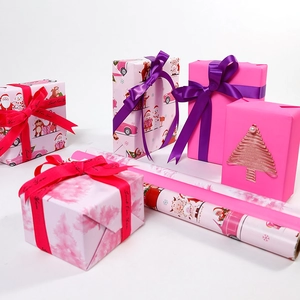 Pink Christmas wrapping paper rolls and gift boxes with cute Santa Claus and snowman prints