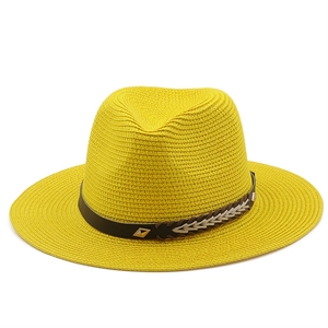 Detail of yellow straw hat with a black textured band and decorative gold buckle