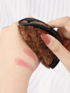 Detailed macro shot of soft brown plush puff removing makeup from hand skin texture
