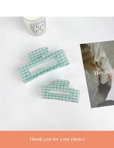 Detail view of mint green and white checkered acrylic hair claw clips in two sizes
