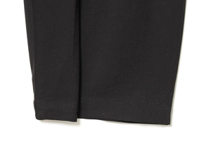 Detailed close-up showing precision double-stitch sewing on black high-waist pleated pants