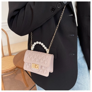 Detail of pink jelly crossbody bag with quilted texture and white pearl handle
