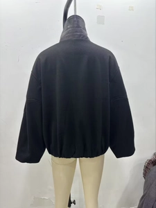 Detail of black textured jacket featuring a leather-拼接 stand collar and elastic hem