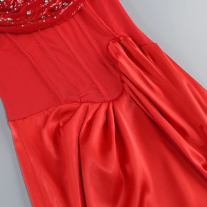 Detailed view of red dress featuring sequin neckline, ribbed bodice and satin pleated skirt