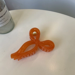 Detailed close-up of an orange ribbon bow hair claw clip with a durable gold spring