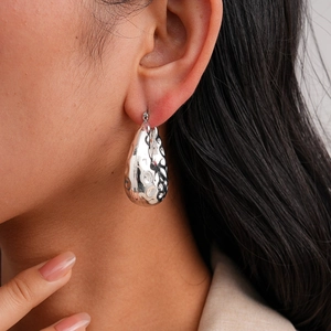 Close-up of silver teardrop earrings with a hammered metal texture for a luxury look