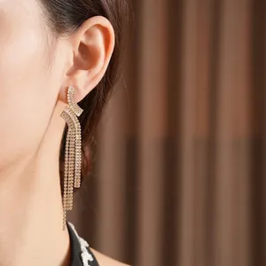 Eleganti orecchini geometrici a nappa in oro con zirconi bianchi su una modella