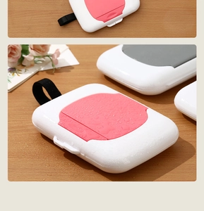 Detail of portable wet wipe case with pink lid and lanyard on wooden surface