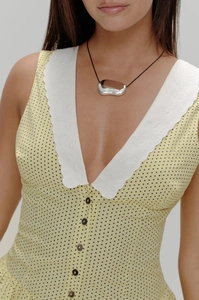 Détail d'une robe jaune à pois avec broderie blanche et boutons noirs devant