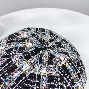 Close-up of colorful tweed plaid beret featuring detailed woven texture and top button detail