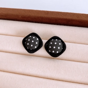 Macro shot of rhombus fabric earrings featuring classic black and white polka dots on velvet