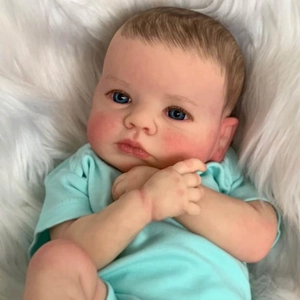 Lifelike 49cm reborn newborn baby doll with blue eyes and green t-shirt on plush background