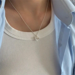 Close-up of minimalist S925 sterling silver heart pendant necklace on a female model