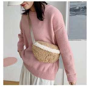 Detail of plush beige crossbody bag with white stripes on a pink sweater background
