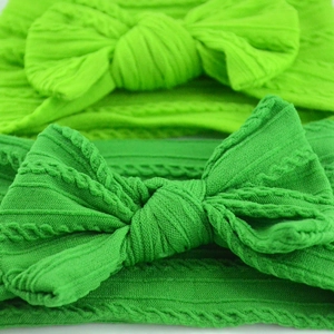 Macro shot of soft jacquard green baby headbands with large textured knit bows