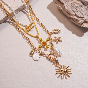 Layered gold necklace set with freshwater pearls, cross pendant, and baroque pearl charms