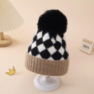 Detailed view of checkered knit baby hat featuring a large black faux fur pom pom
