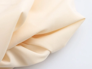 Close-up of the elegant beige fabric texture and smooth folding detail on the dress