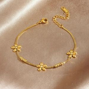 Gold stainless steel box chain bracelet featuring three dimensional floral charms with crystals