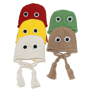 Detailed view of colorful frog beanies featuring cartoon eyes and braided tassels