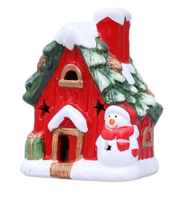Close-up of ceramic Christmas house with snowman and star-shaped cutouts for LED light