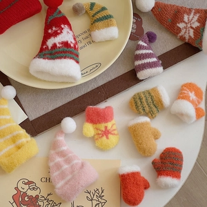 Close-up of mini knitted Christmas hats and gloves with reindeer patterns and pom-poms