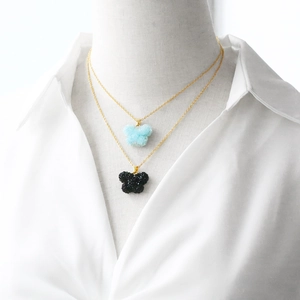 Collier avec pendentif papillon doré en bleu clair et noir sur une chemise blanche