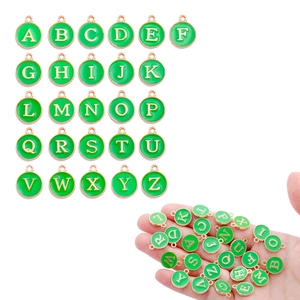 Detail of green round letter charms from A to Z with gold borders for DIY jewelry making