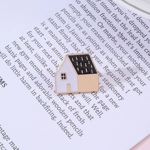 Minimalist house-shaped metal brooch with black and white enamel finish on paper background