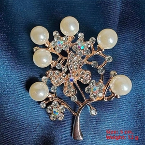Macro view of a 5cm floral brooch with imitation pearls and rhinestones on blue fabric