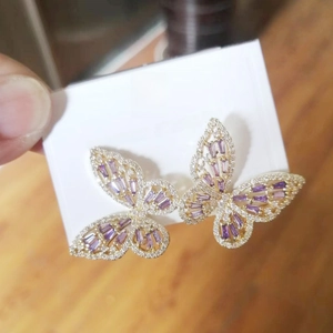 Macro shot of butterfly earrings with gold plating, purple stones and white zircon stones