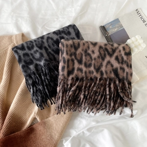 Close-up of leopard print scarves with fringe detail in grey and brown cashmere-like fabric