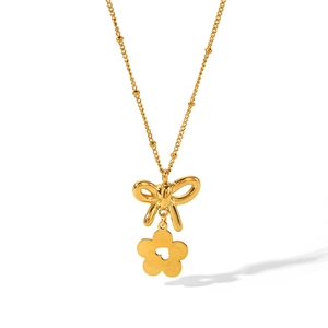 Close-up of 18K gold bow and flower pendant necklace with elegant beaded chain detail