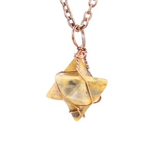 Macro detail of hand-wrapped copper wire on a natural stone Merkaba star pendant