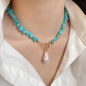 Detail of ethnic turquoise beaded necklace with gold OT buckle and baroque pearl on model