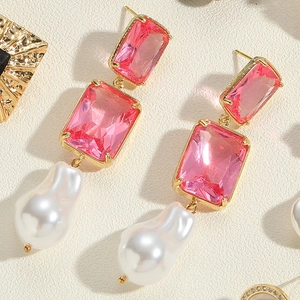 Close-up of baroque pearl earrings with pink crystals on gold-tone metal base