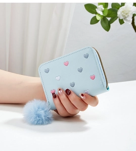 Close-up of light blue purse with colorful heart embroidery and plush charm