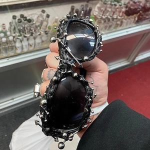 Detail view of gothic punk black sunglasses featuring silver metal spikes and stud rivets