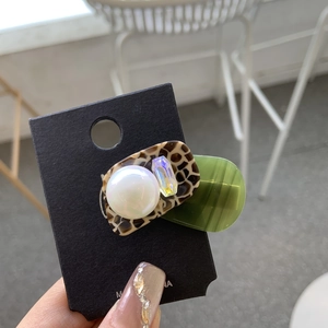 Close-up of acetic acid hair clip with pearl and colorful resin charms on a display card