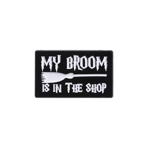 Black enamel rectangular pin with My Broom Is In The Shop quote and broom graphic