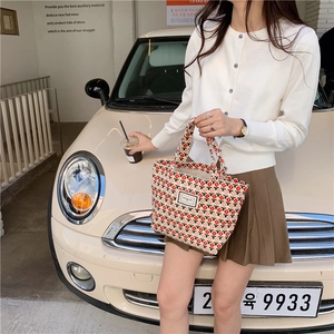 Close-up of corduroy tulip pattern tote bag held by model near a vintage mini car