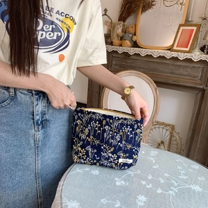 Close-up of dark blue canvas cosmetic bag with floral embroidery and brand label