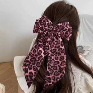 Detail of pink leopard print bow hair clip with long ribbons on brunette hair