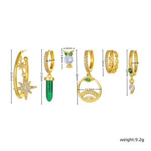 Detailed view of gold starburst and owl stud earring set with green gemstone pendants