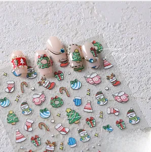 Detailed view of Christmas nail art stickers with snowman and tree patterns on nails