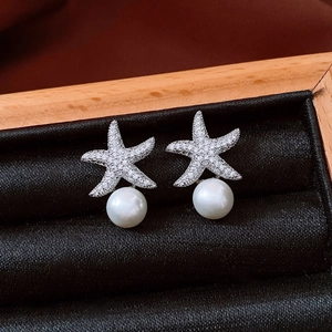 Macro shot of silver starfish pearl earrings with cubic zirconia in a jewelry box